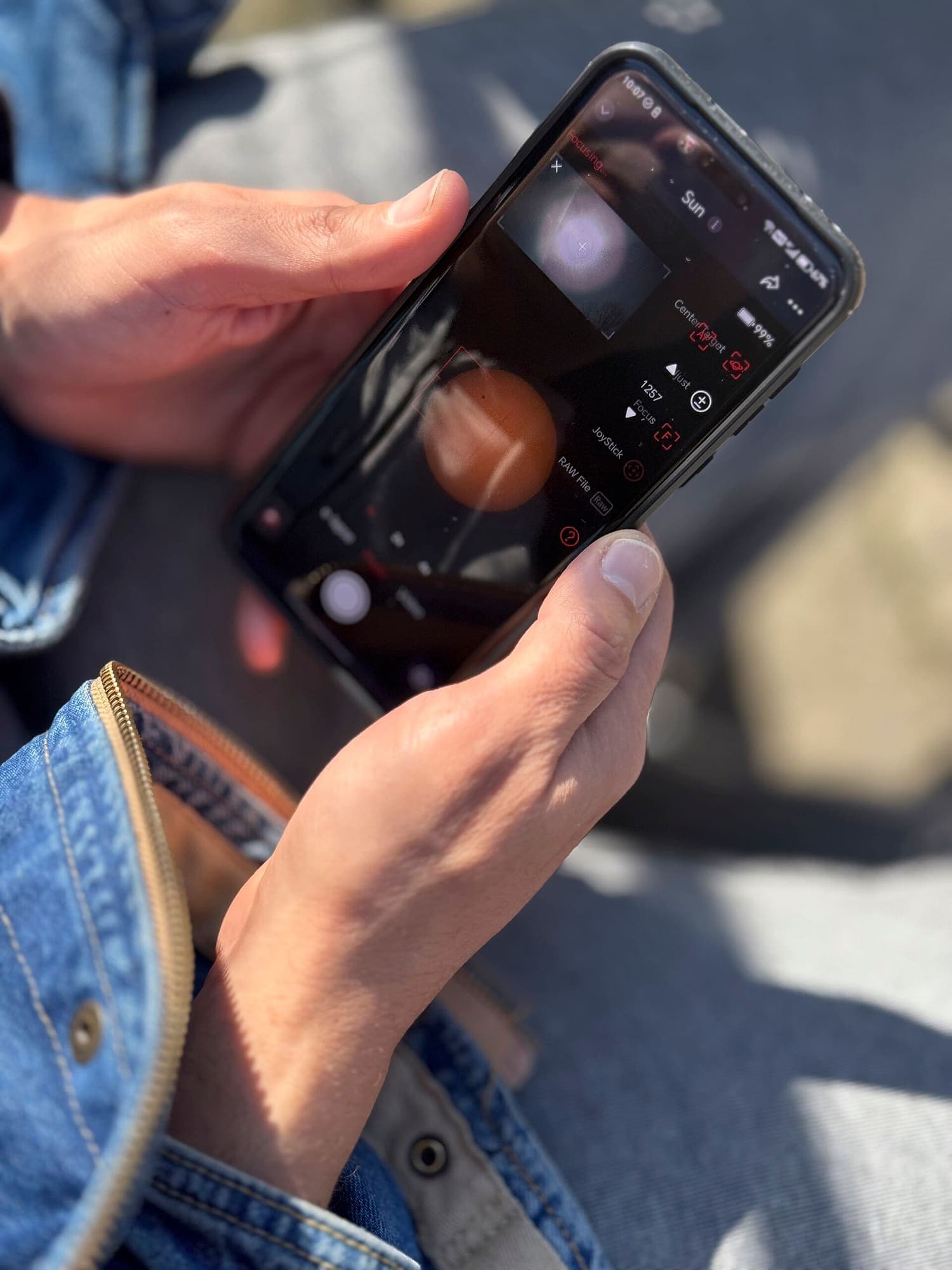 Placeholder — a phone held above a printed photo book page, showing a video overlay